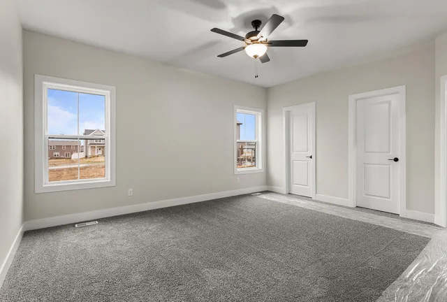 an empty room with a chandelier fan and windows