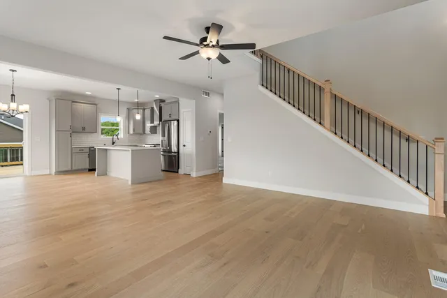 a view of a kitchen with a sink a refrigerator a ceiling fan and wooden floor