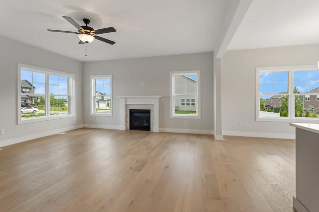 an empty room with wooden floor a ceiling fan and windows