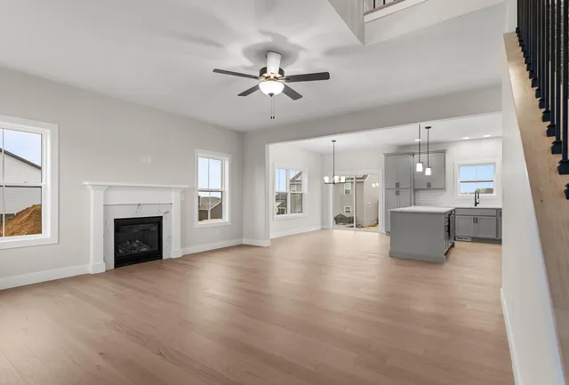 a view of a livingroom with a fireplace a ceiling fan and windows