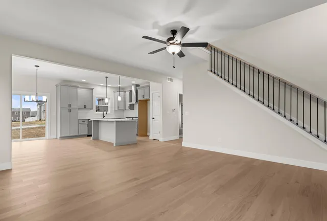 a view of an empty room with wooden floor and a kitchen
