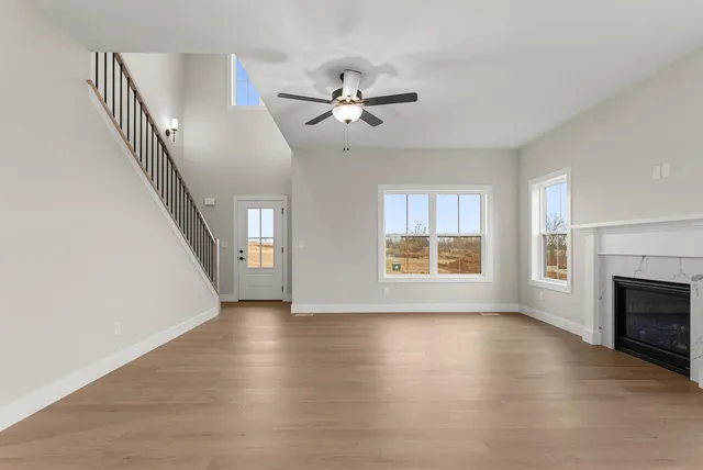 a view of an empty room with chandelier fan and wooden floor