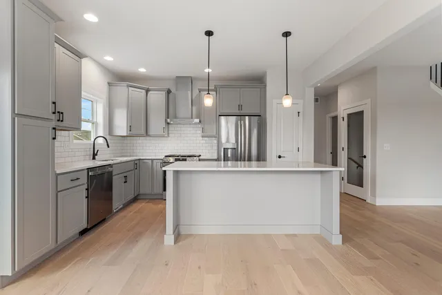 a large kitchen with stainless steel appliances sink refrigerator and wooden floor