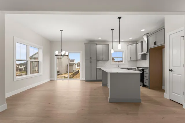 a kitchen with stainless steel appliances kitchen island granite countertop a refrigerator a oven a sink with a dining table and chairs