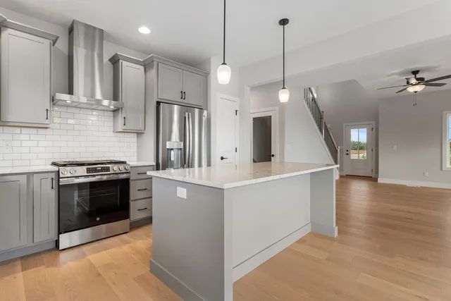 a kitchen with stainless steel appliances kitchen island wooden cabinets a stove a sink and a refrigerator