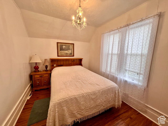 350 West Main Street Emery, UT 84522 - Photo 10 of 28 Bedroom featuring vaulted ceiling, a chandelier, dark wood-style flooring, and a textured ceiling