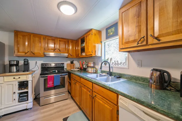 a kitchen with stainless steel appliances granite countertop a sink dishwasher stove and cabinets with wooden floor