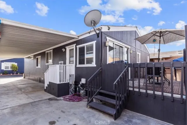 a view of a patio with a table and chairs under an umbrella with a barbeque