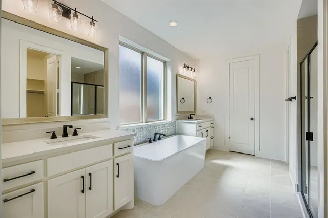 a spacious bathroom with a double vanity sink mirror and bathtub
