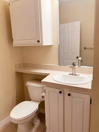 a bathroom with a granite countertop toilet sink and mirror