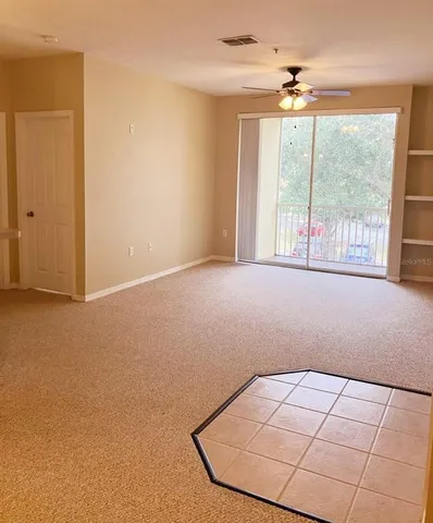 an empty room with chandelier fan and windows