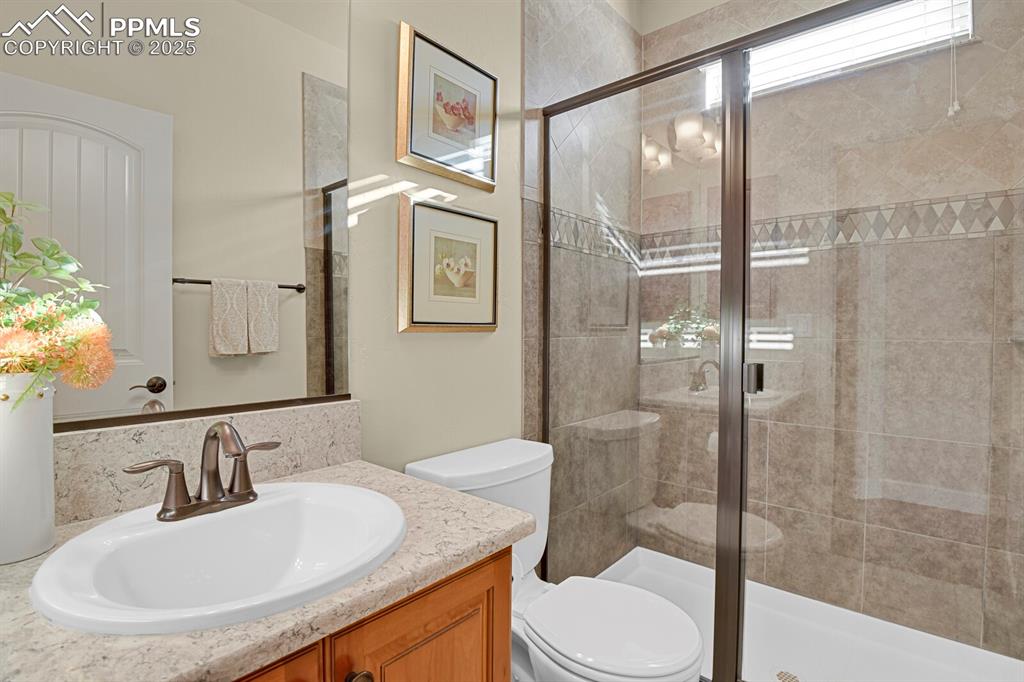 13015 Cake Bread Heights Colorado Springs, CO 80921 - Photo 23 of 45 a bathroom with a granite countertop sink toilet a mirror and shower