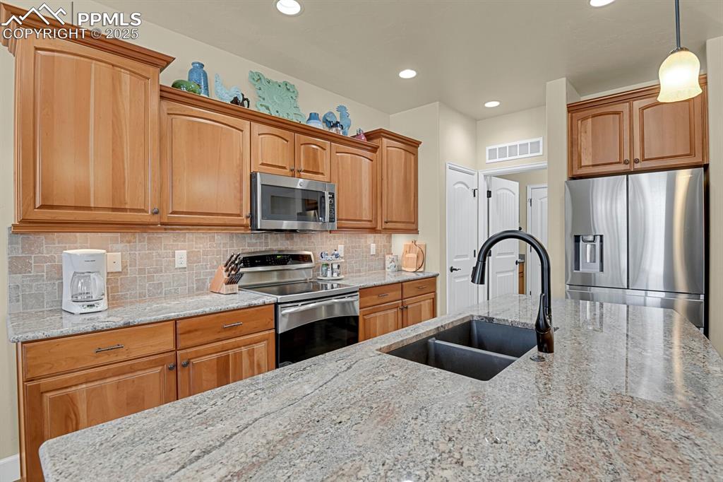 13015 Cake Bread Heights Colorado Springs, CO 80921 - Photo 3 of 45 a kitchen with stainless steel appliances granite countertop a stove top oven a sink dishwasher and white cabinets with wooden floor