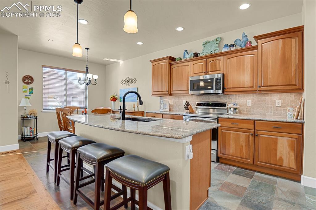 13015 Cake Bread Heights Colorado Springs, CO 80921 - Photo 6 of 45 a kitchen with stainless steel appliances granite countertop a sink a stove a microwave a dining table and chairs