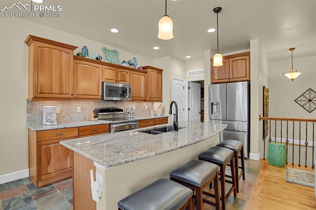13015 Cake Bread Heights Colorado Springs, CO 80921 - Photo 7 of 45 a kitchen with stainless steel appliances granite countertop a sink a stove a refrigerator and island