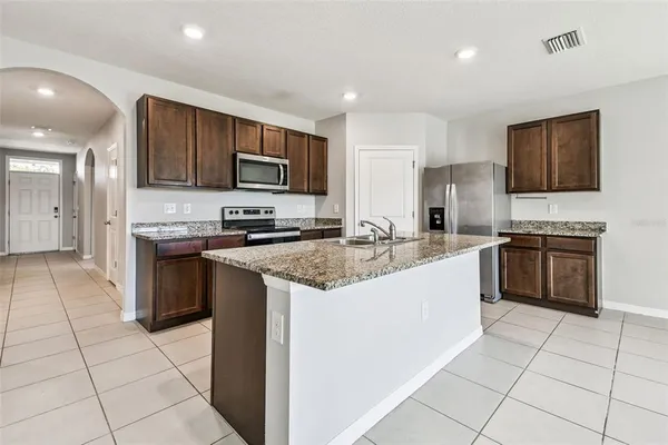 a kitchen with stainless steel appliances granite countertop a sink stove and refrigerator