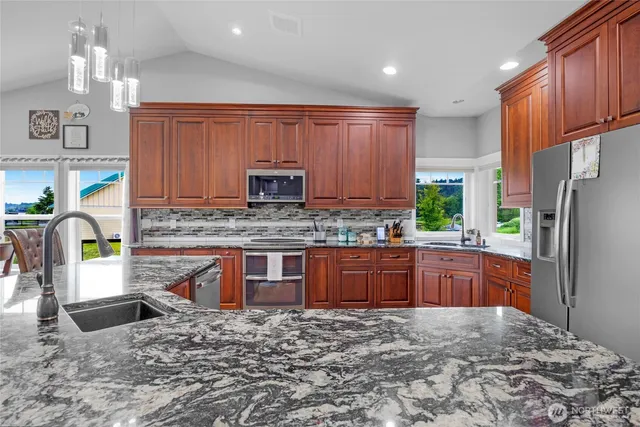 a kitchen with stainless steel appliances granite countertop a sink refrigerator stove microwave and cabinets