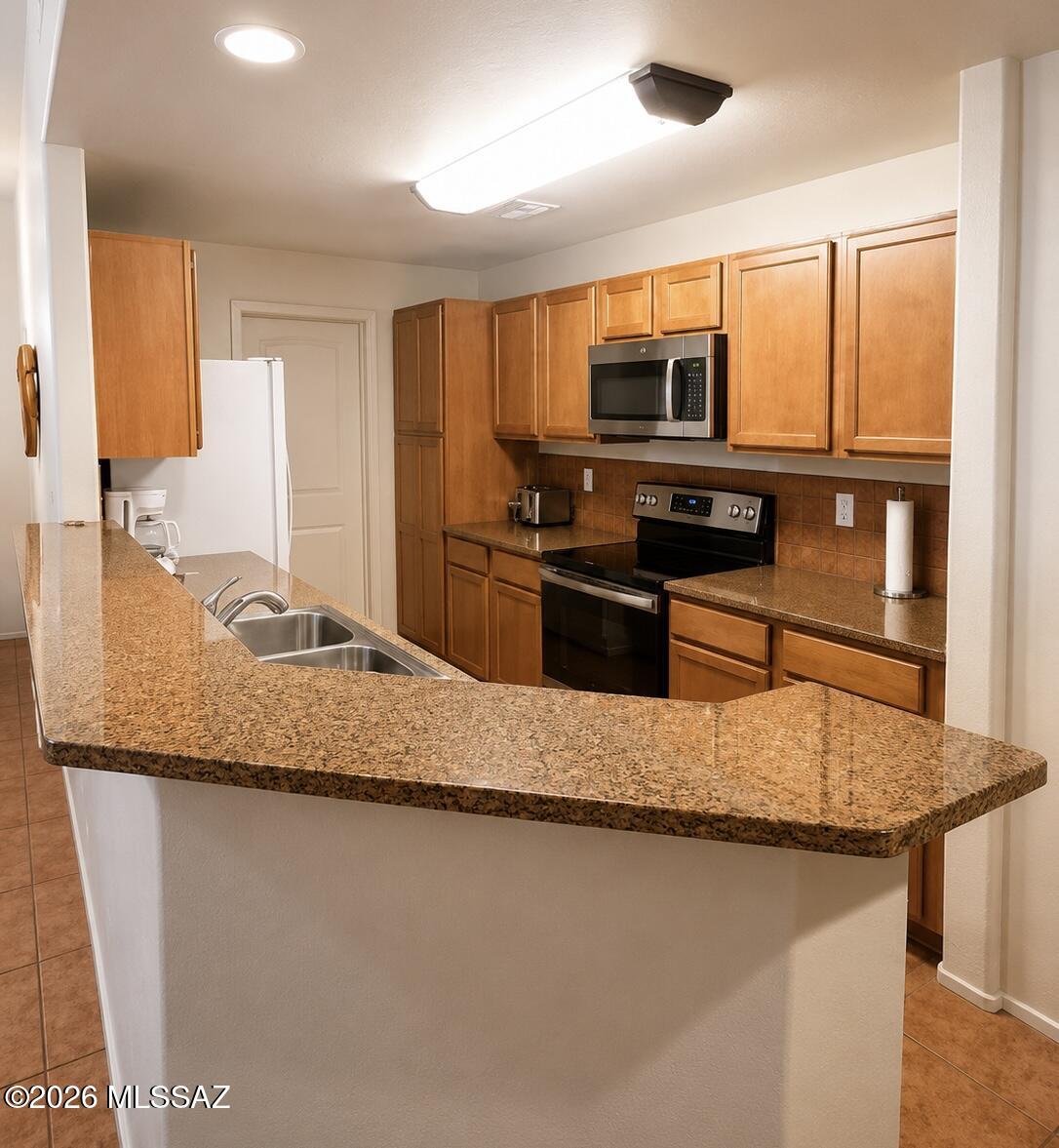 2018 East River Road, Unit 102 Tucson, AZ 85718 - Photo 10 of 25 a kitchen with stainless steel appliances granite countertop a sink refrigerator and microwave