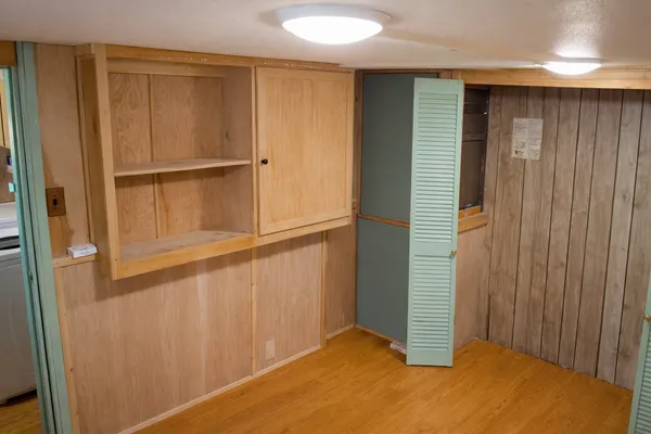an empty room with wooden floor and cabinet