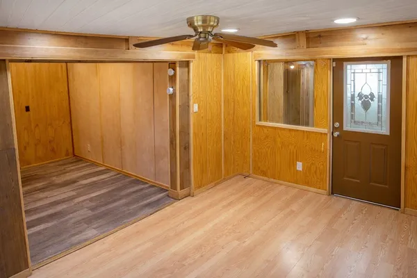 a view of a hallway with wooden floor and a bathroom