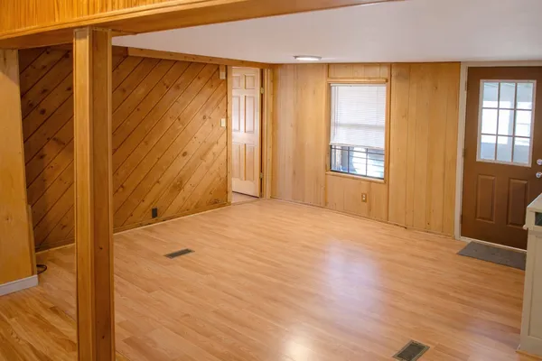 a view of an empty room with wooden floor and a window