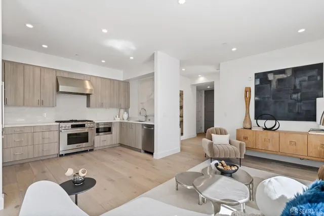 a living room with furniture a rug and kitchen view