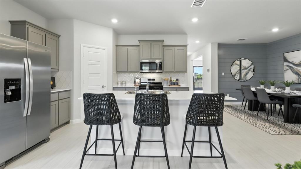 304 Perk Street Keene, TX 76059 - Photo 2 of 34 a kitchen with stainless steel appliances kitchen island granite countertop a refrigerator a stove a microwave oven a dining table and chairs with wooden floor