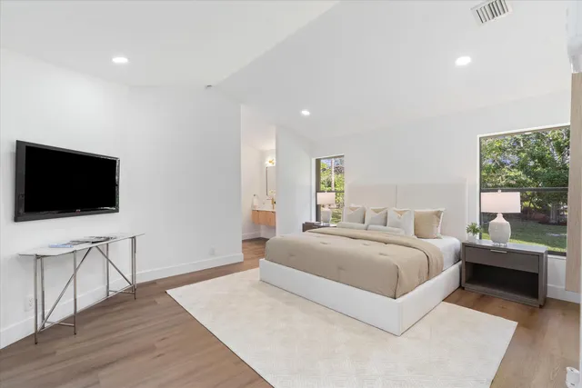 a spacious bedroom with a bed and a flat screen tv