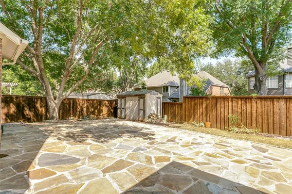 a view of a backyard with large trees and wooden fence