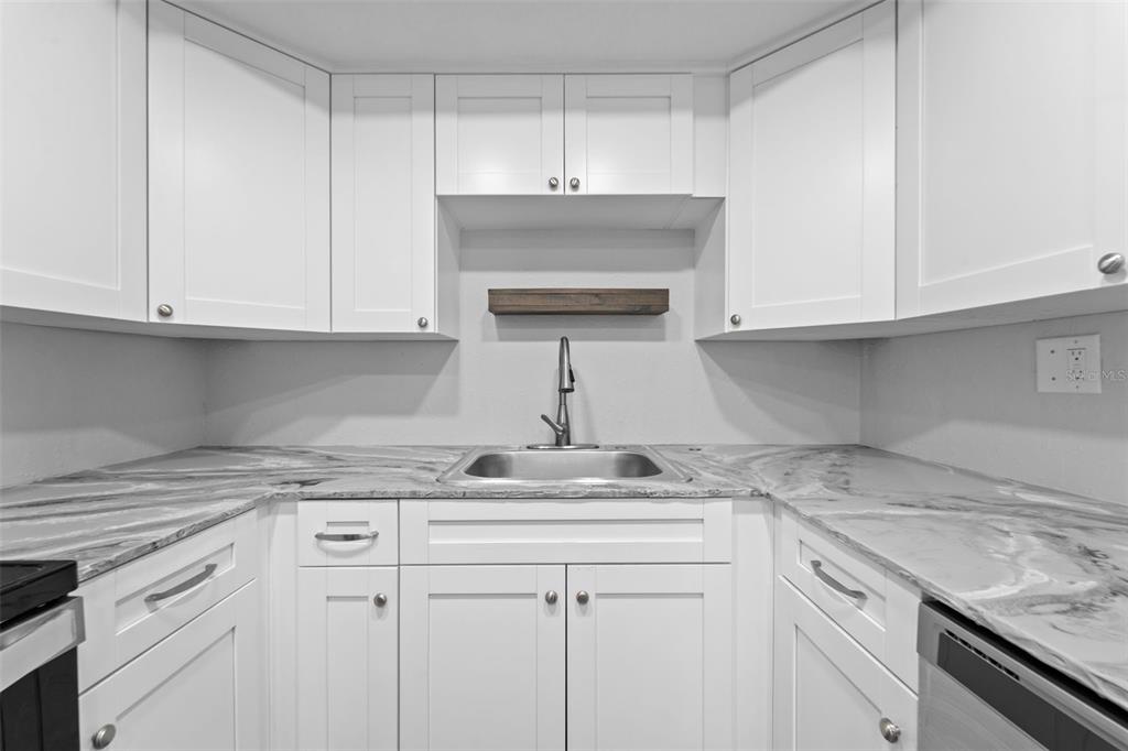 4238 Glissade Drive New Port Richey, FL 34652 - Photo 14 of 62 a kitchen with stainless steel appliances granite countertop a sink dishwasher a stove and white cabinets