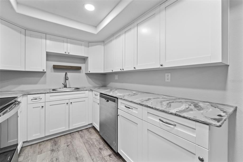 4238 Glissade Drive New Port Richey, FL 34652 - Photo 15 of 62 a kitchen with granite countertop white cabinets and white appliances