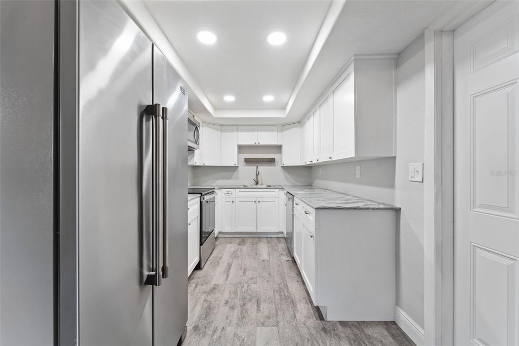 4238 Glissade Drive New Port Richey, FL 34652 - Photo 18 of 62 a kitchen with white cabinets and white appliances