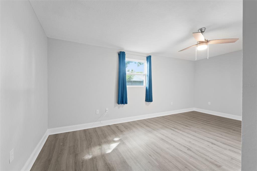 4238 Glissade Drive New Port Richey, FL 34652 - Photo 27 of 62 an empty room with wooden floor chandelier fan and windows