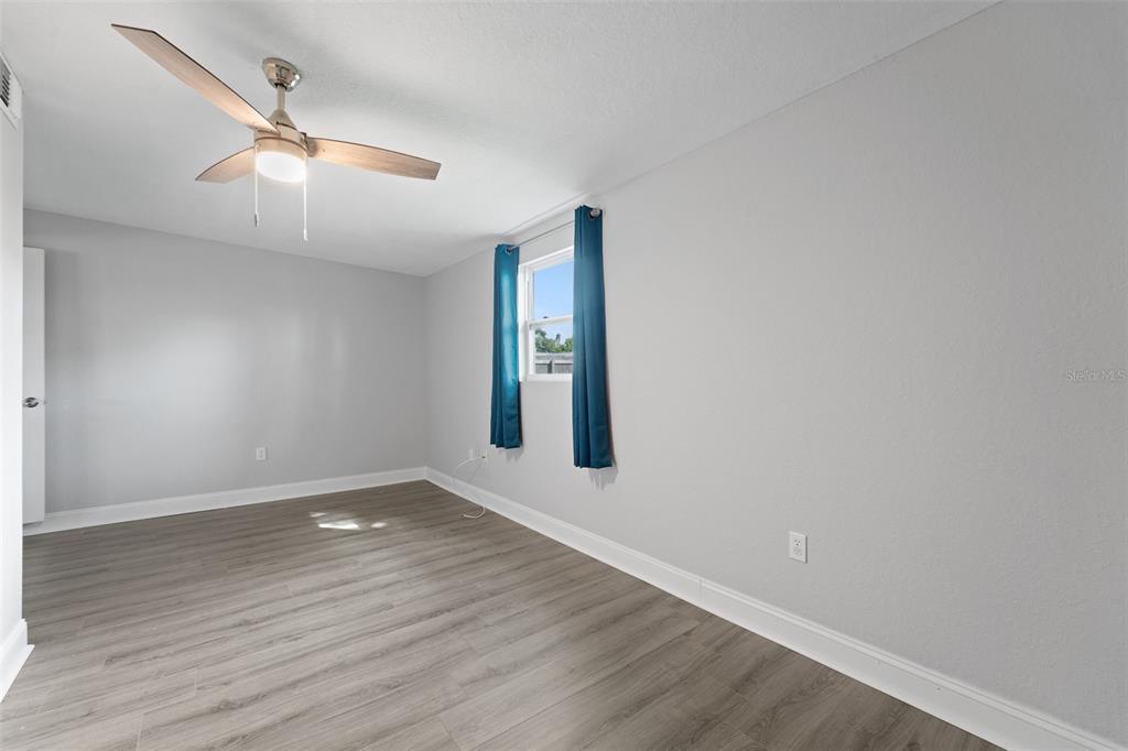 4238 Glissade Drive New Port Richey, FL 34652 - Photo 30 of 62 an empty room with wooden floor chandelier fan and windows