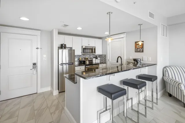 a kitchen with stainless steel appliances kitchen island granite countertop a refrigerator and a stove top oven