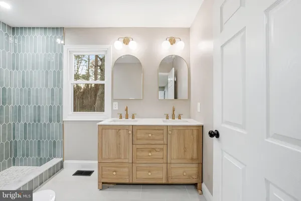 a en suite bathroom with double vanity a mirror a vanity and a shower