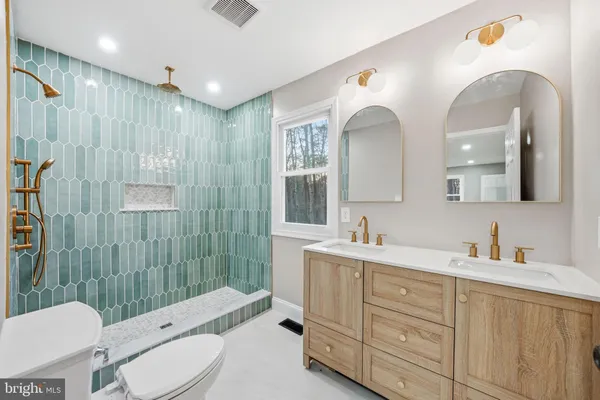 a bathroom with a double vanity sink toilet mirror and shower