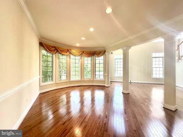 a view of an empty room with wooden floor fireplace and a window