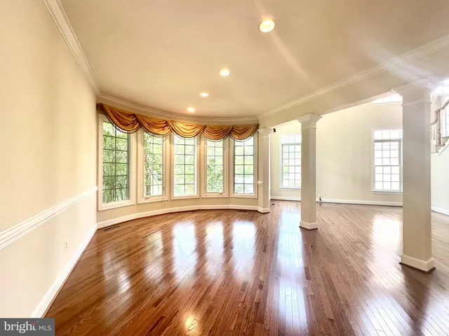 a view of an empty room with wooden floor fireplace and a window