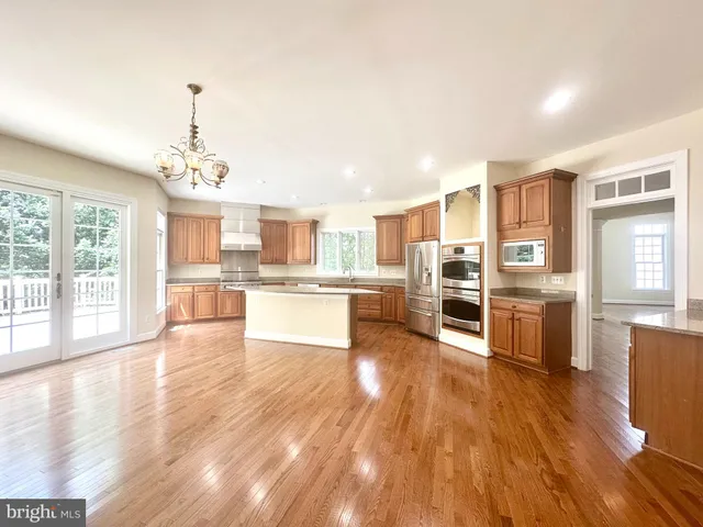 a view of an empty room with wooden floor fireplace and a window