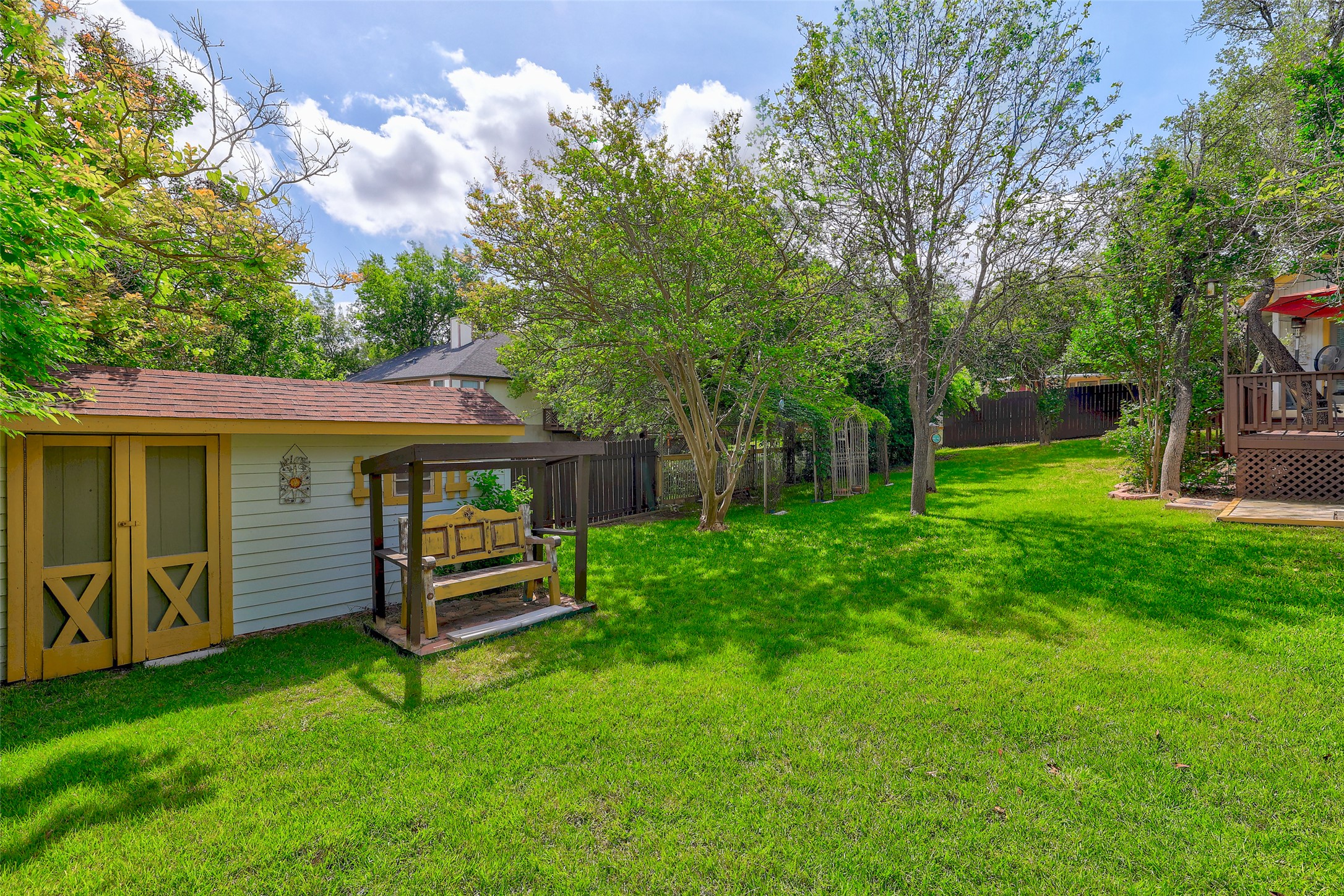 110 South Ridge Circle Georgetown, TX 78628 - Photo 36 of 37 Expansive grassy lawn with established trees, featuring a detached shed with double barn doors and a covered swing bench