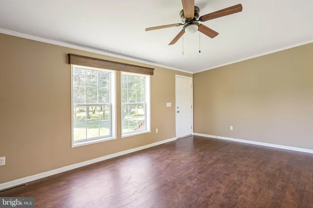 a view of an empty room with a window and wooden floor