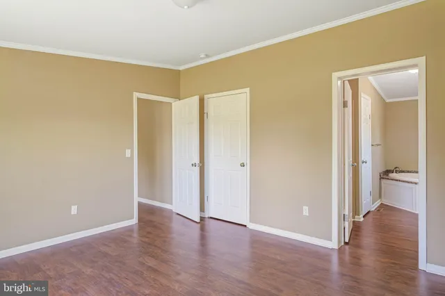 a view of an empty room with wooden floor and a bathroom