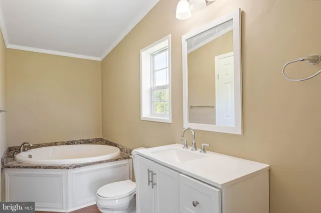 a bathroom with a granite countertop toilet a sink and a window