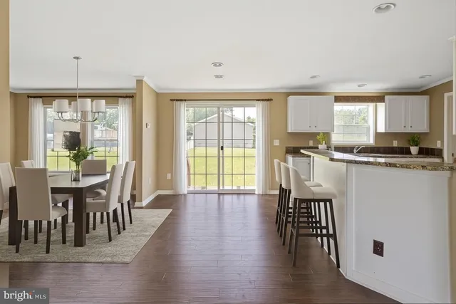 a kitchen with granite countertop a stove a sink a dining table and chairs with wooden floor