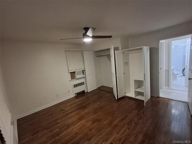 an empty room with wooden floor closet and windows