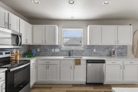 a living room with furniture a flat screen tv and kitchen view
