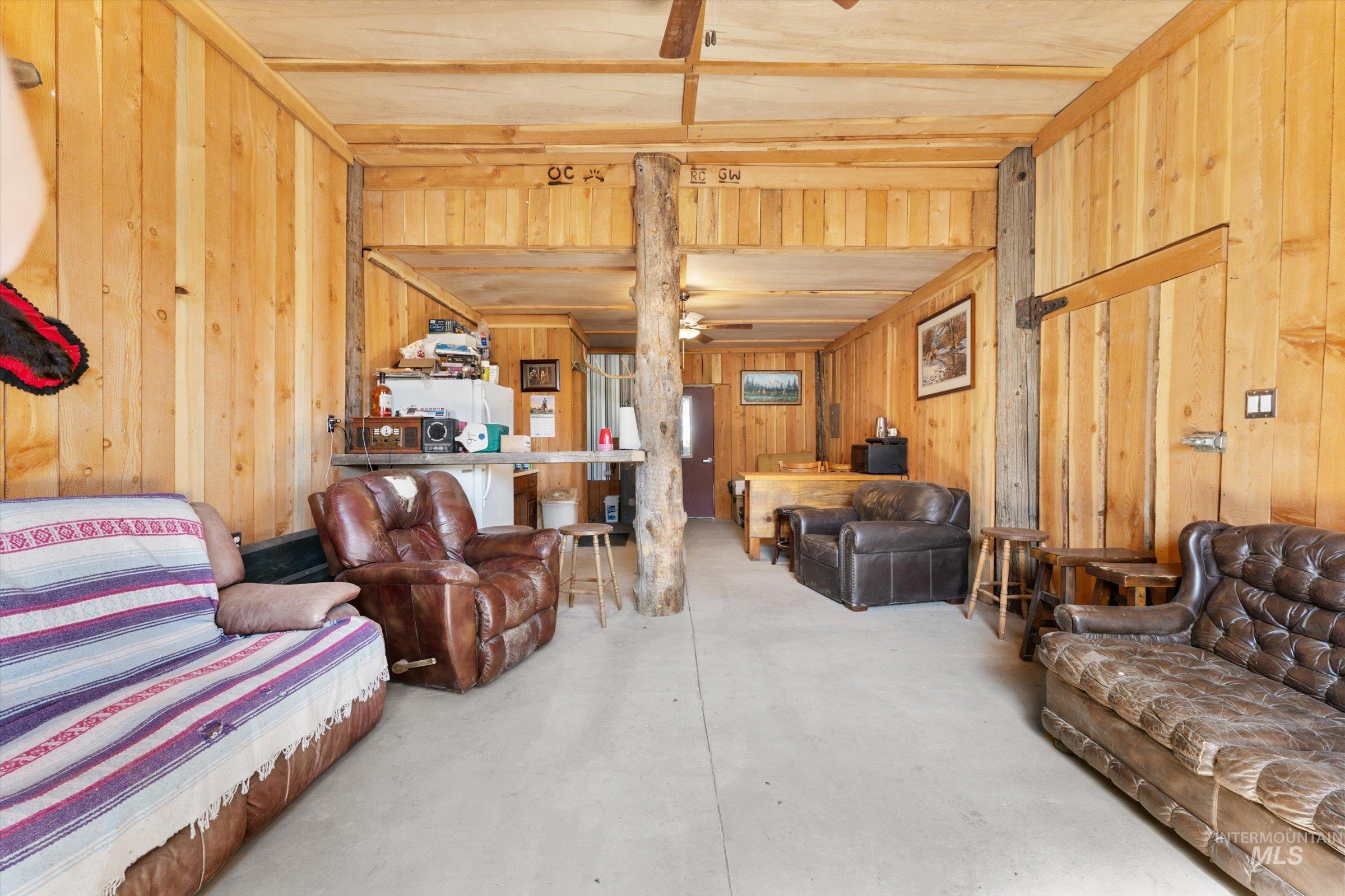 11555 Liberty Road Sweet, ID 83670 - Photo 6 of 49 Living area featuring concrete floors, ceiling fan, and wooden walls
