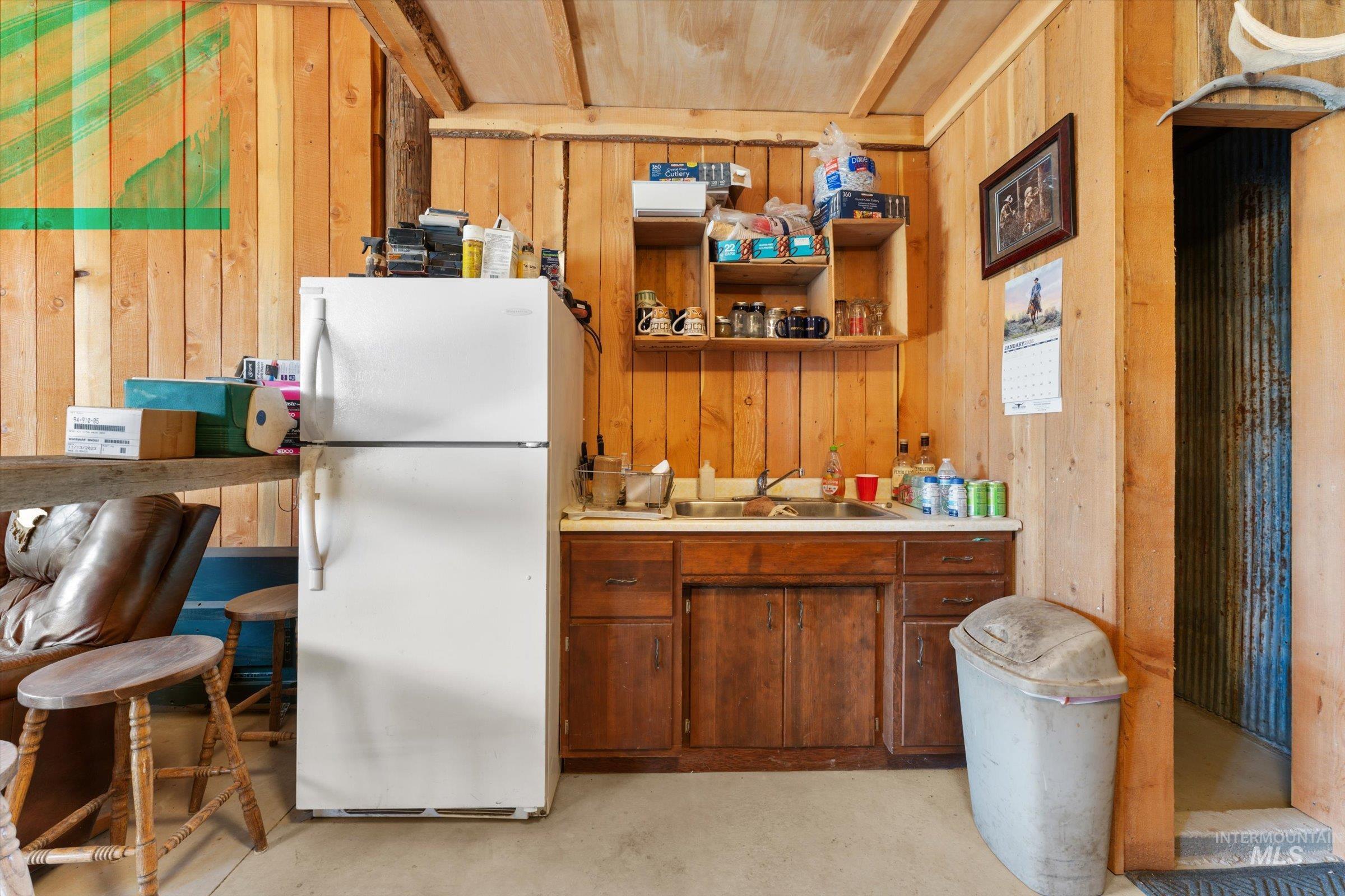 11555 Liberty Road Sweet, ID 83670 - Photo 9 of 49 Kitchen with freestanding refrigerator, light countertops, open shelves, wood walls, and concrete flooring