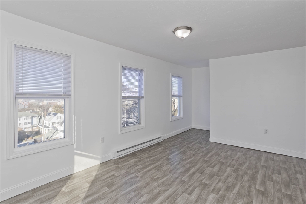 107 Eastern Avenue Worcester, MA 01605 - Photo 17 of 38 a view of an empty room with window and wooden floor
